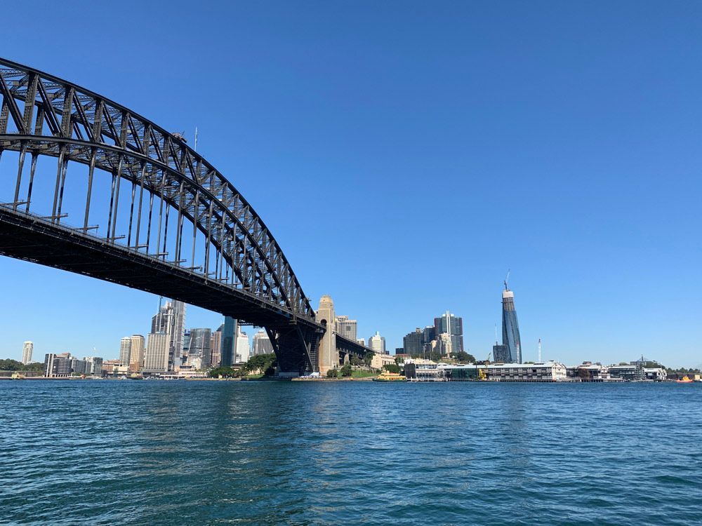 A Bridge Over A Body Of Water With A City In The Background 
