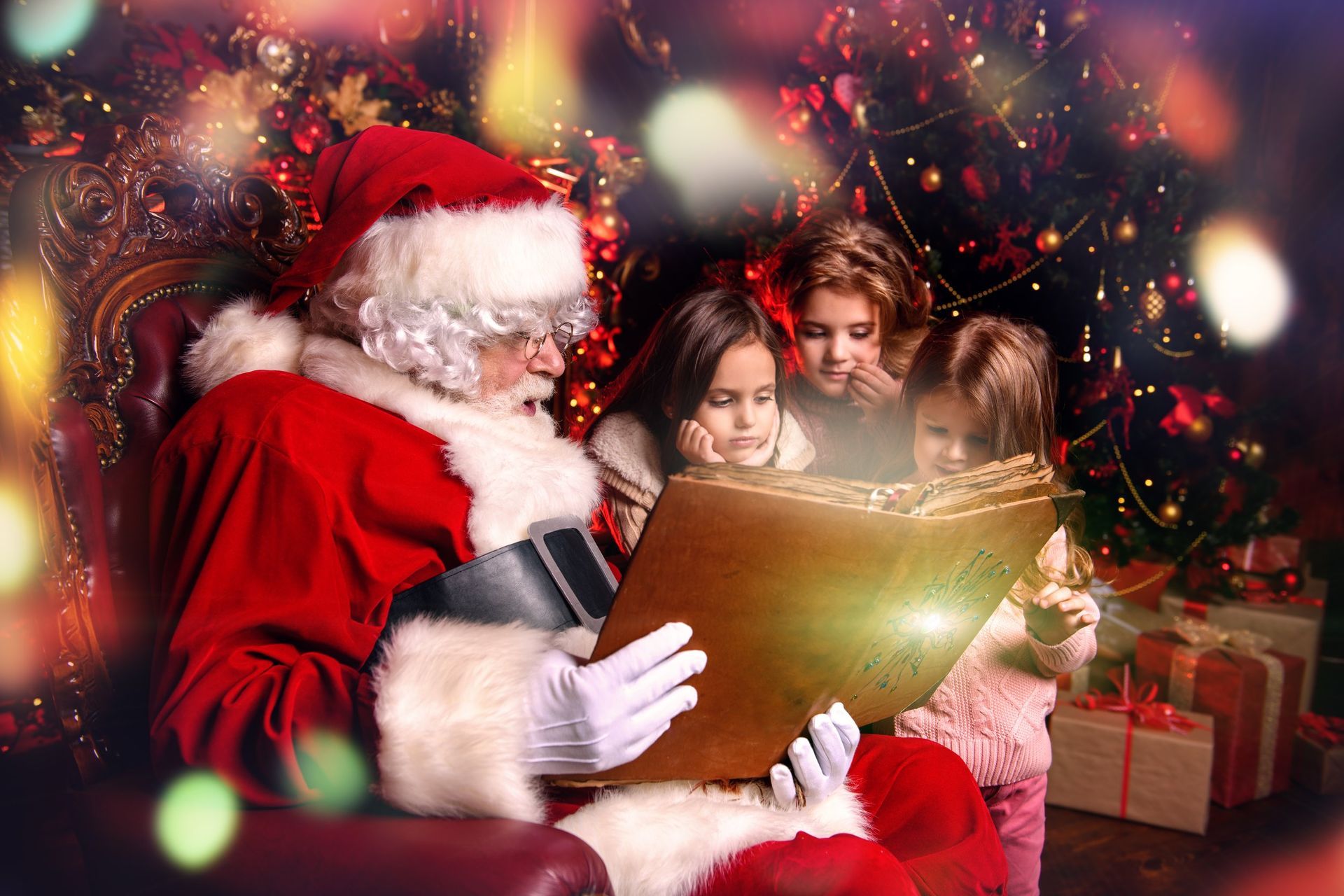 Santa reading a glowing book to three children amid Christmas lights and gifts