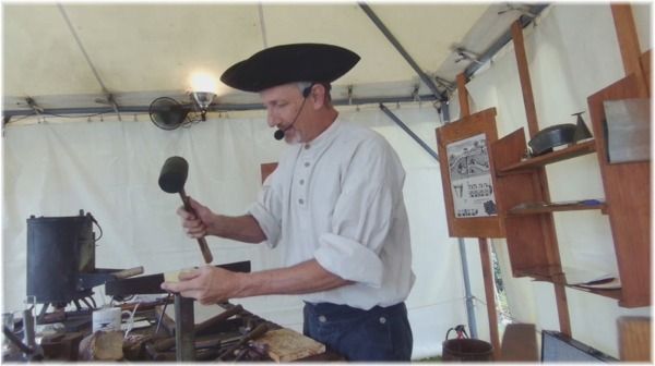 Man in a black hat cooking over a camp stove inside a white tent