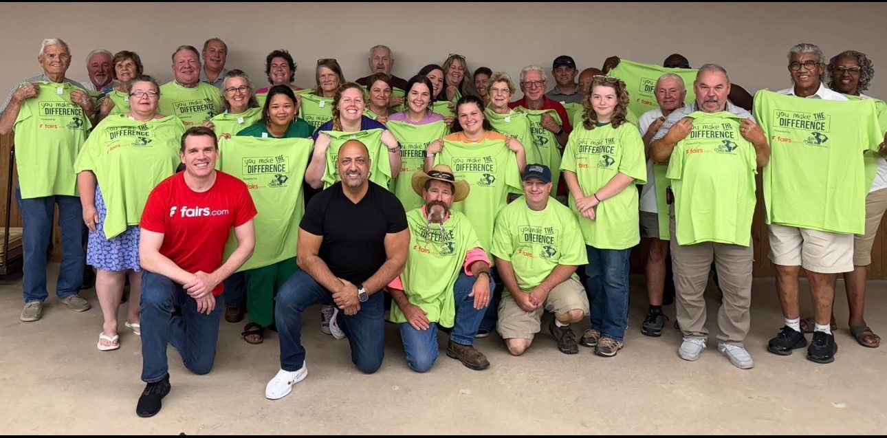 Group of volunteers in bright green shirts posing together indoors; two people kneel in front.