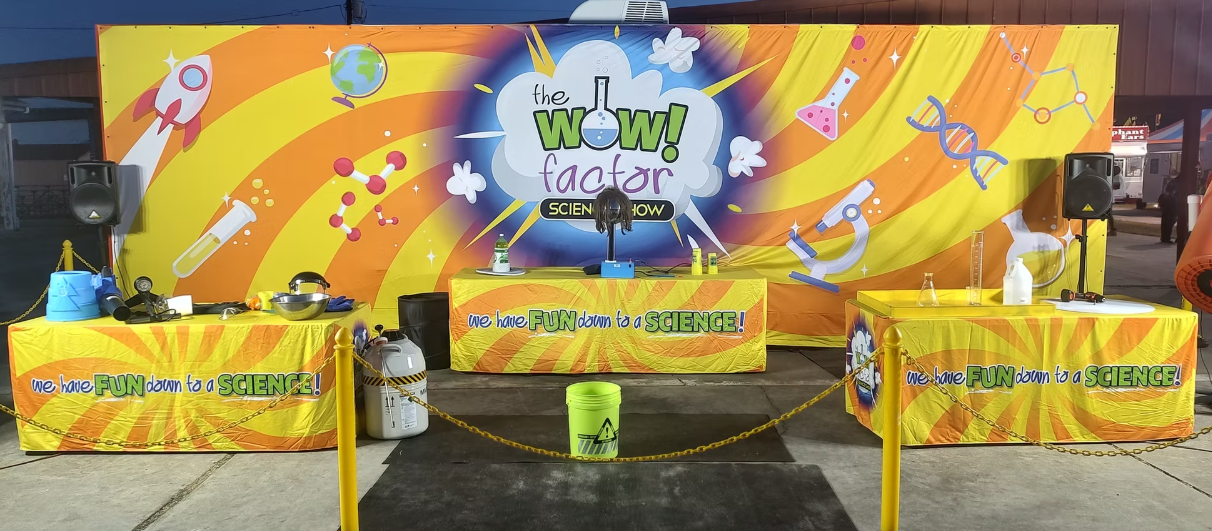 Bright yellow stage with colorful rocket-themed backdrop and banners at an event setup