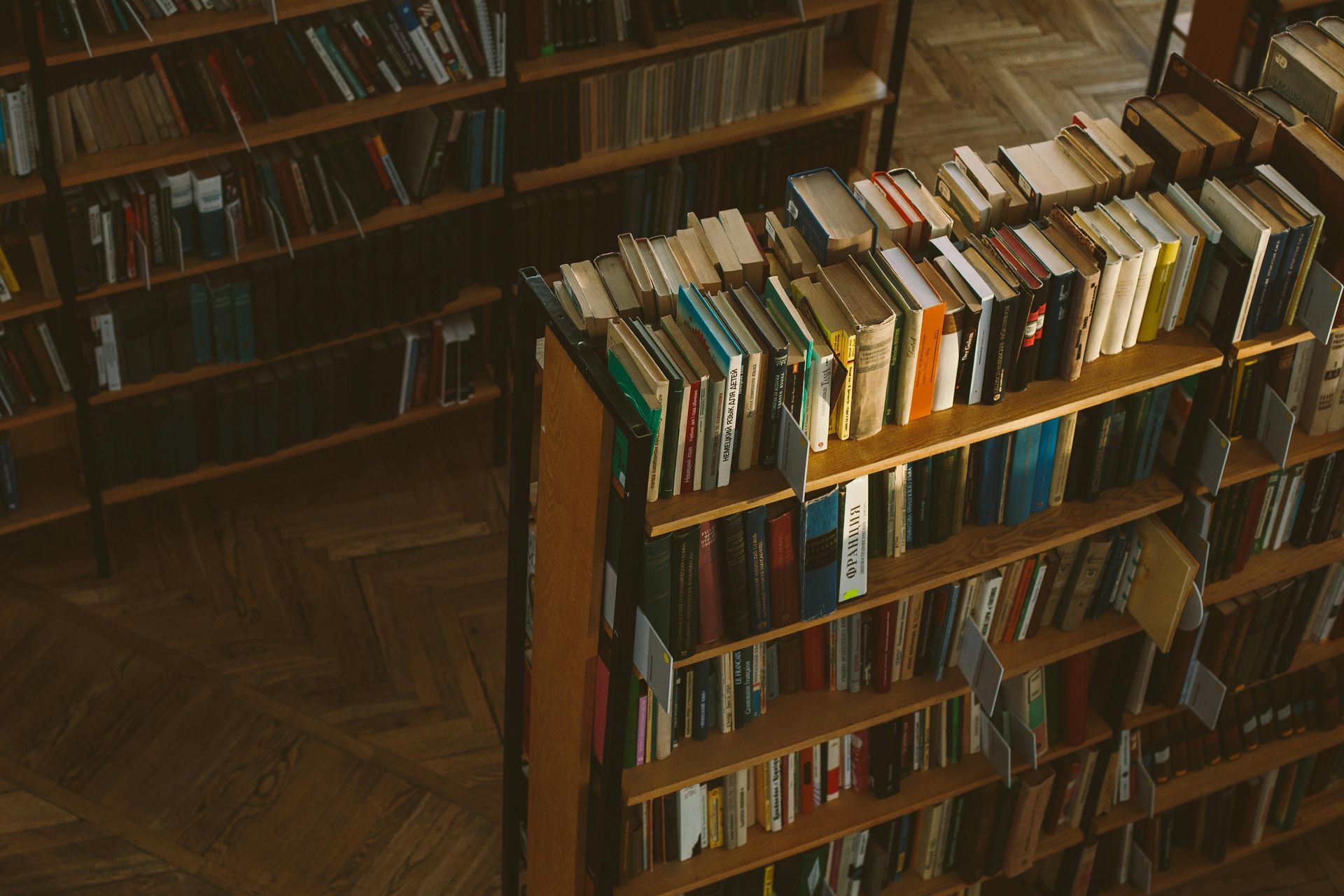A bookstore aisle with tall shelves filled with books, lit by warm sunlight.