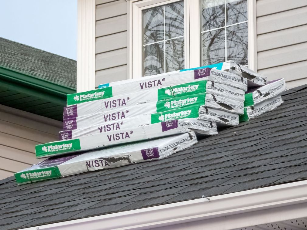 Stacked bundles of Malarkey Vista asphalt roof shingles resting on a residential house roof.