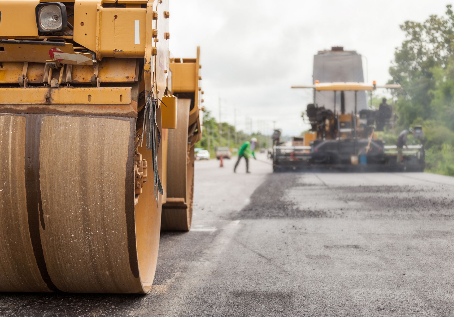 Road roller compacting fresh asphalt on a highway during road construction. Road roller compacting fresh asphalt on a highway during road construction.