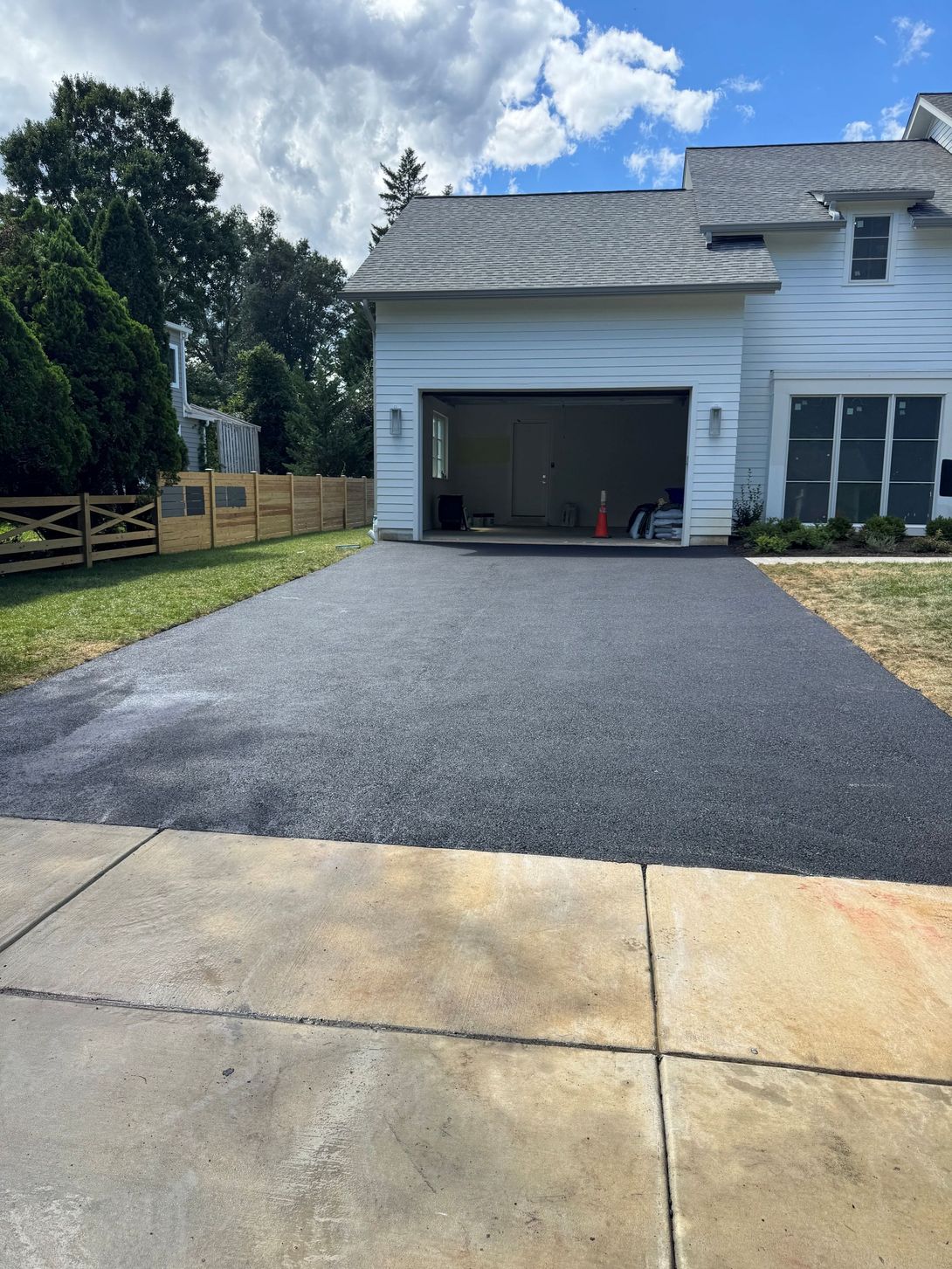 A newly laid dark gray gravel driveway leading to a garage next to a section of old concrete driveway.