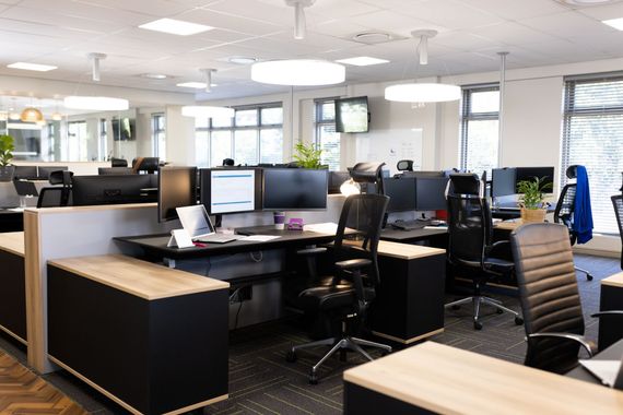 Office cleaners mopping and tidying a bright workspace with desks and plants