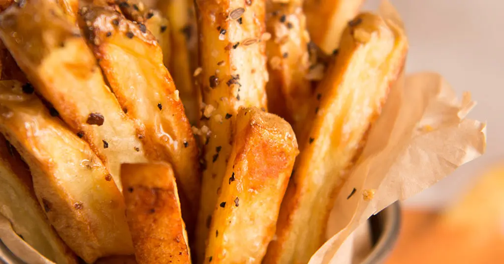 A close up of french fries in a basket on a table.
