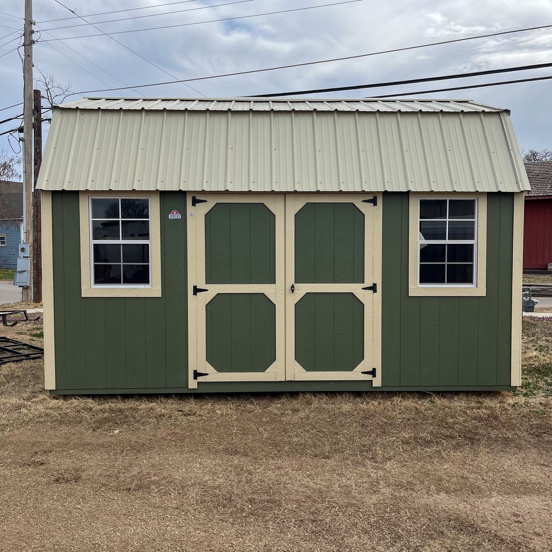 Un cobertizo verde y blanco con dos puertas y dos ventanas