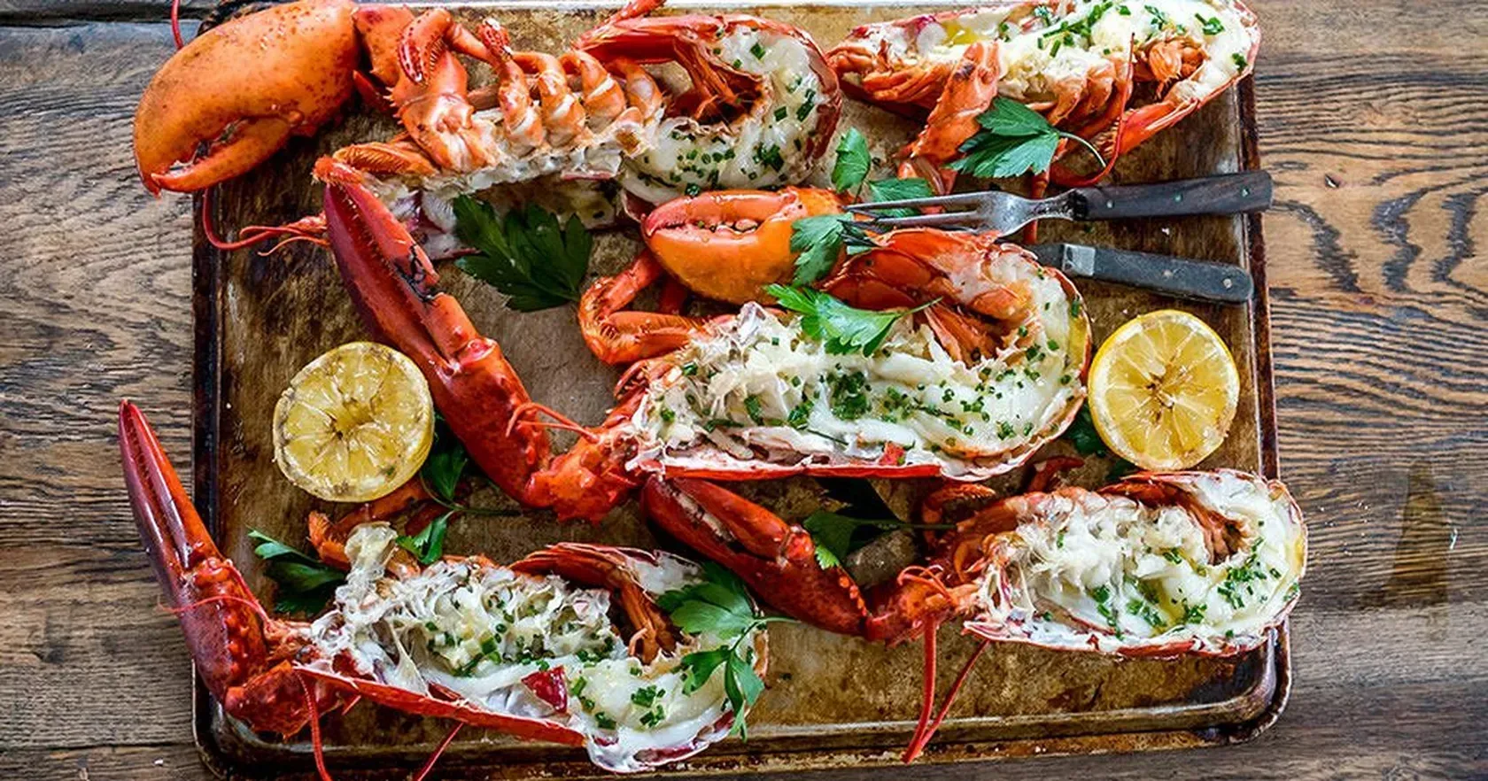 A tray of cooked lobsters on a wooden table.