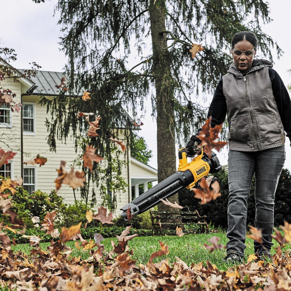 a woman blowing leaves with a dewalt leaf blower