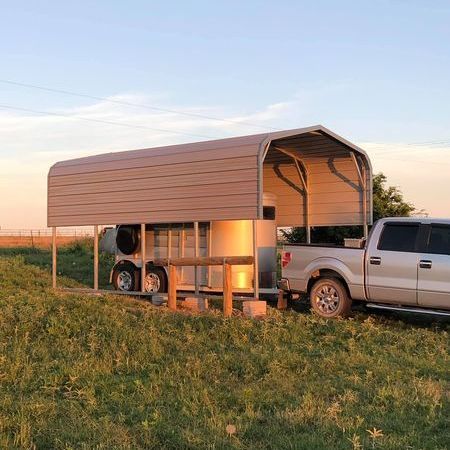 Un camión está estacionado en un campo con un remolque adjunto.