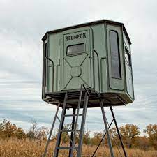 A deer stand with a ladder attached to it is sitting in the middle of a field.