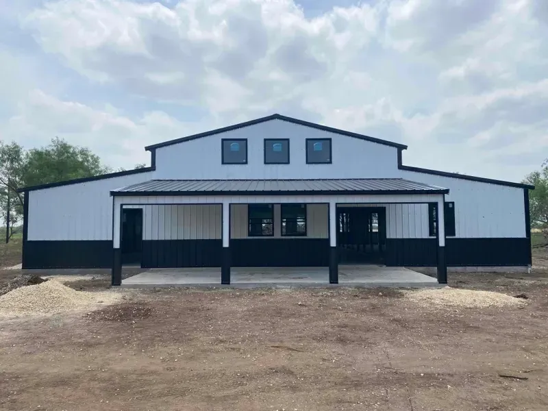White farmhouse-style building with black trim and a covered front porch under a cloudy sky