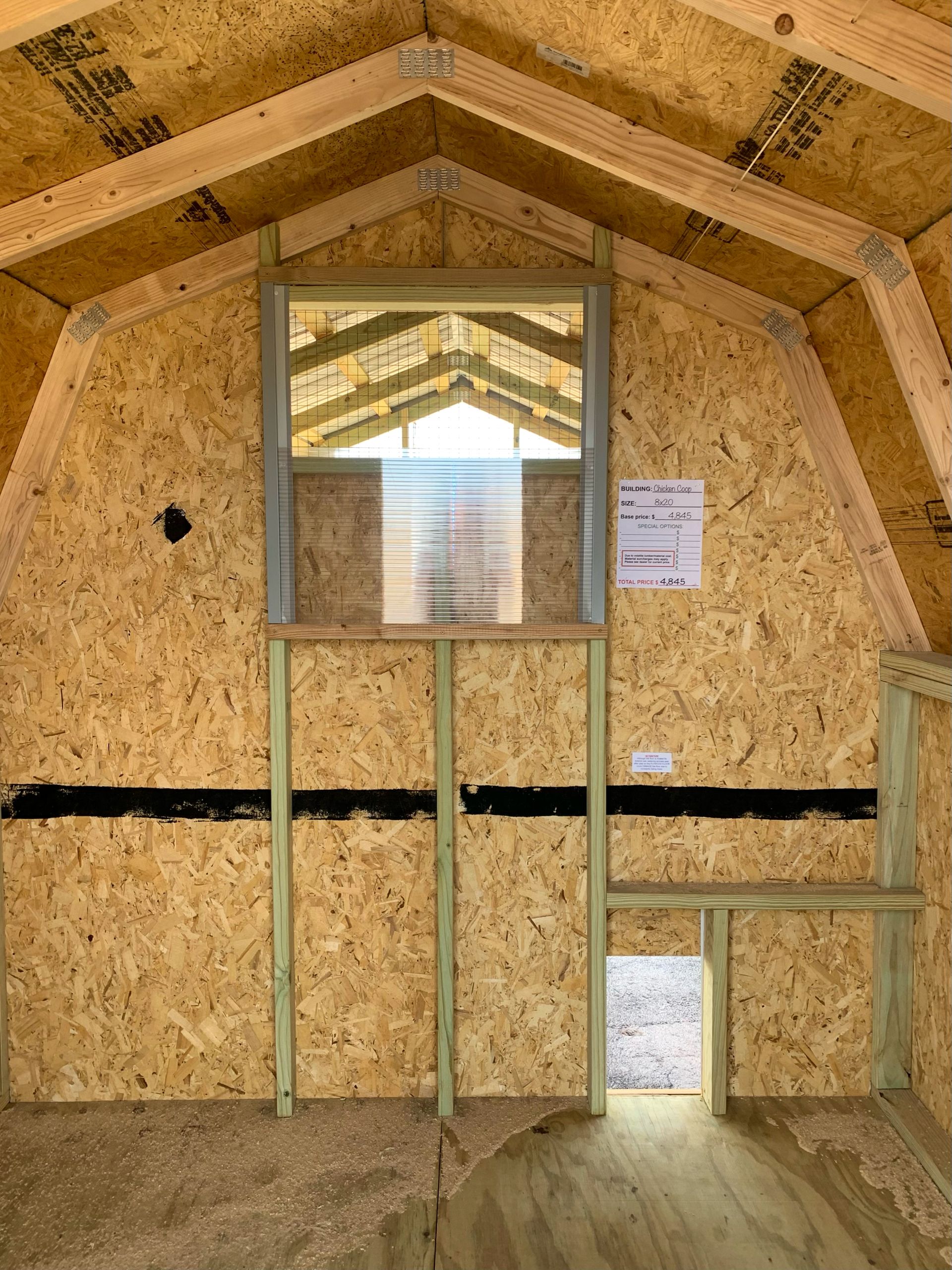 El interior de un cobertizo de madera con una ventana y una puerta.