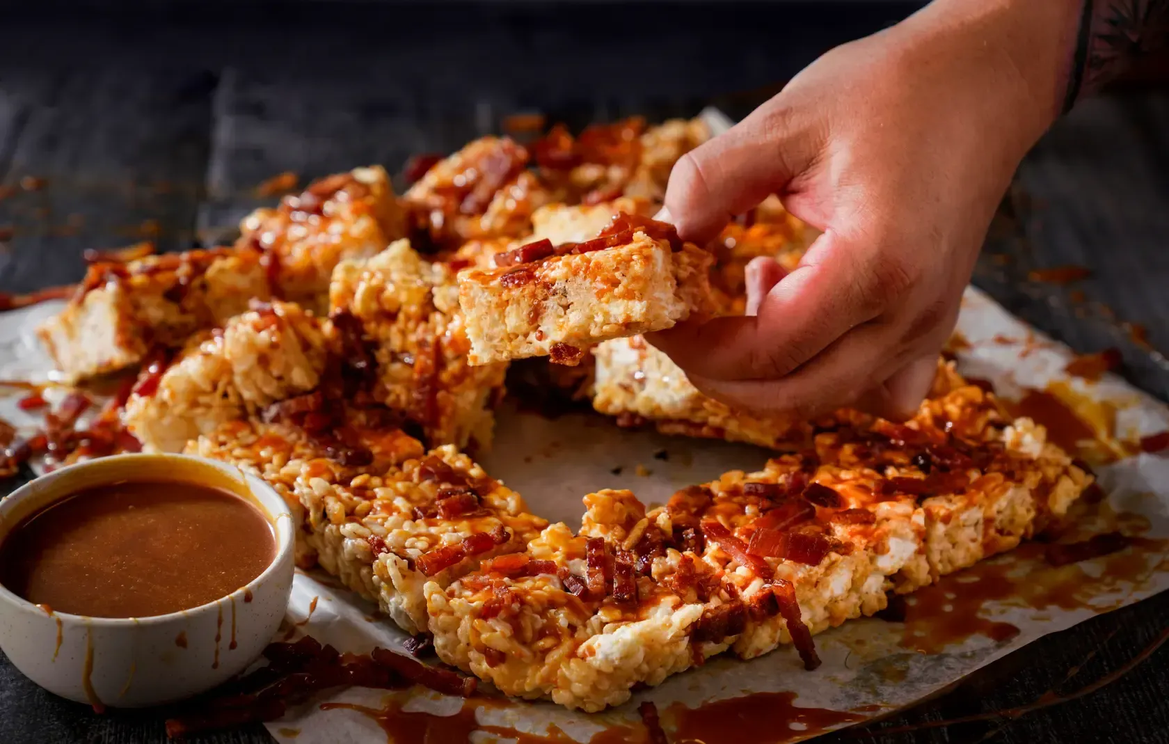 A person is taking a piece of pizza from a pizza wreath.