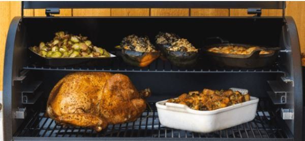 A grill with a turkey and casserole dishes on it