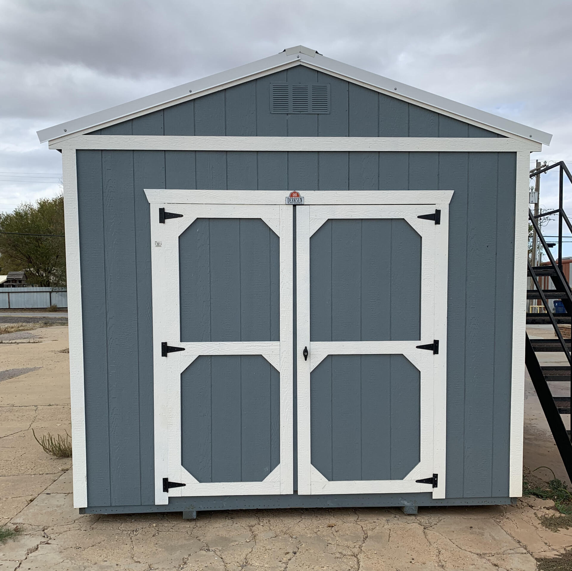 a gray and white shed with a staircase in front of it .