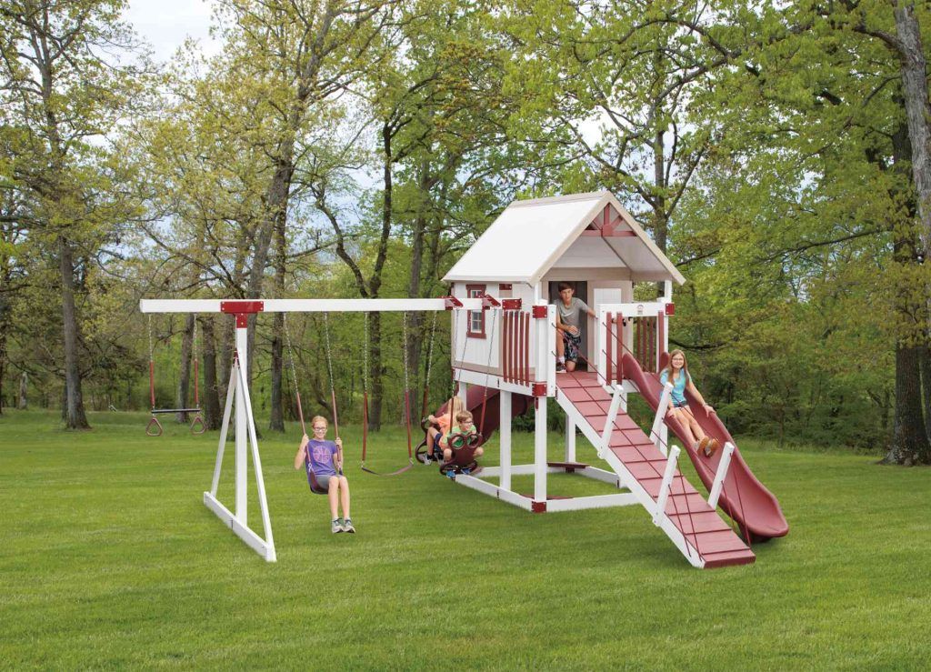A girl is sitting on a swing in front of a playground.