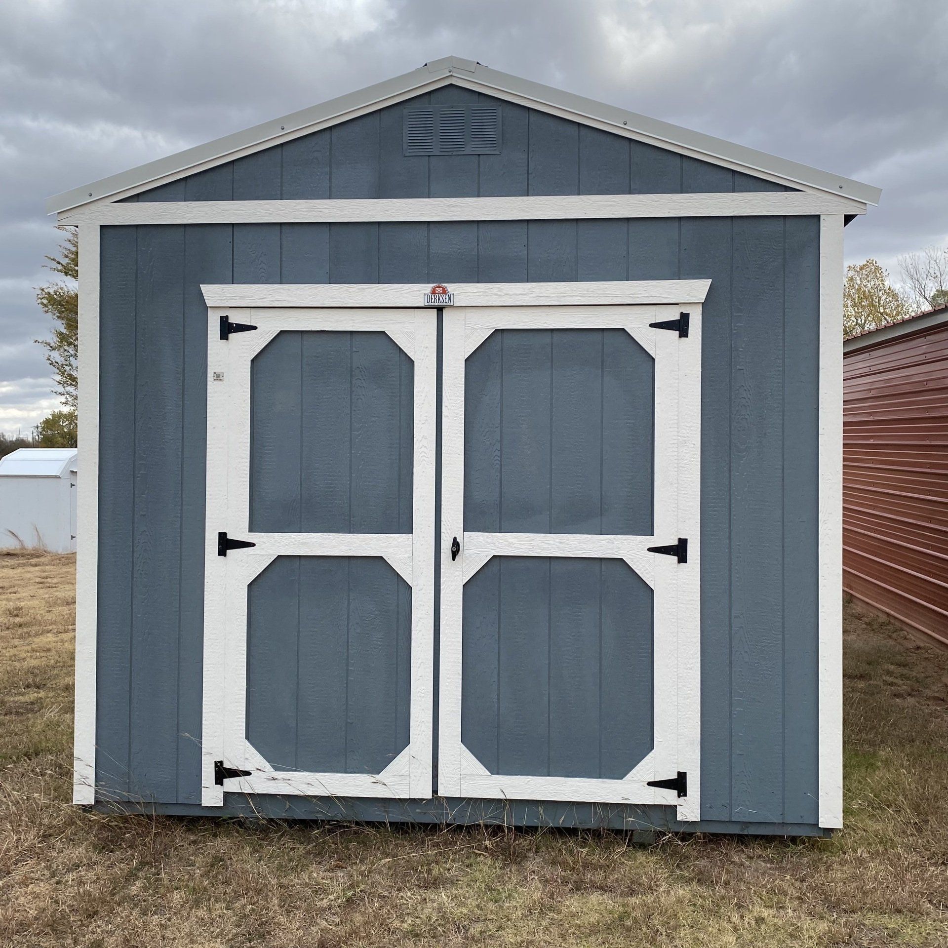 Un cobertizo azul y blanco con las puertas abiertas