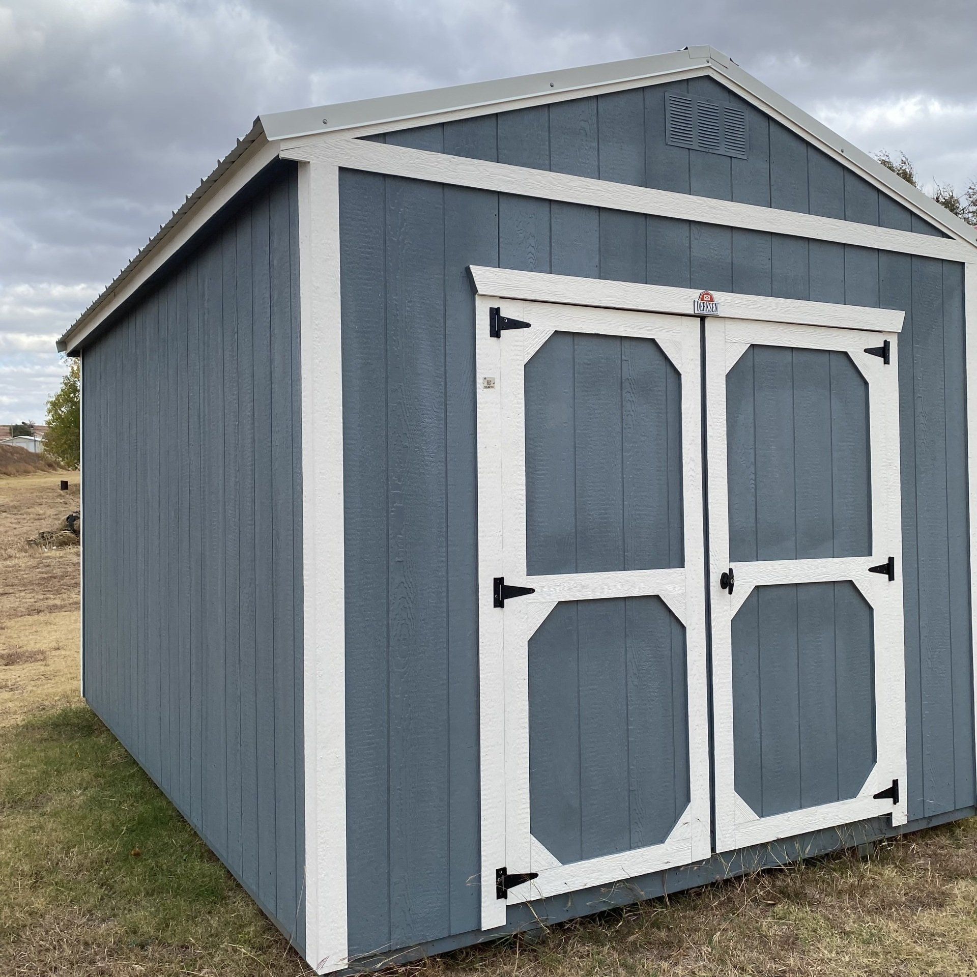Un cobertizo azul y blanco con techo y puertas