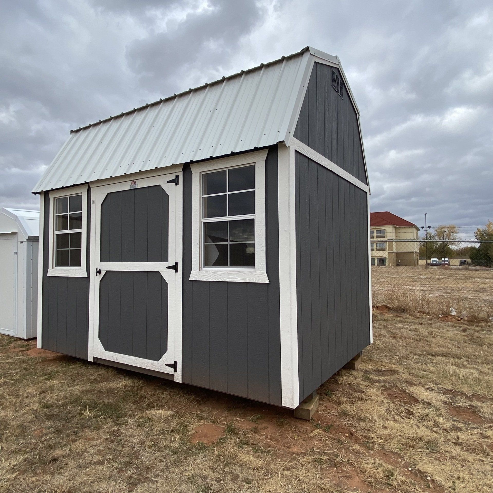 A gray and white shed with a white roof