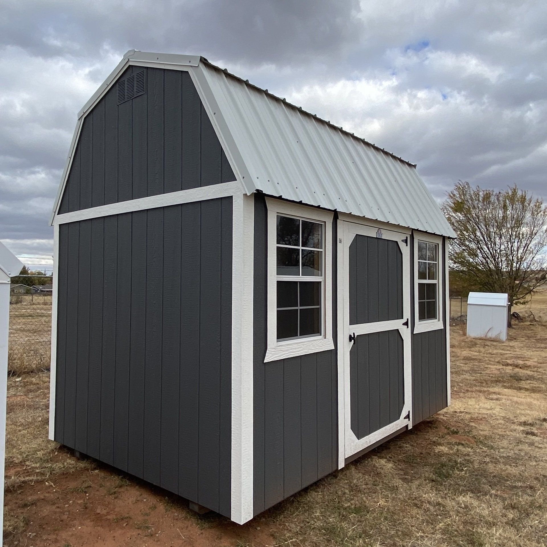 A gray and white side Lofted barn shed with a white roof