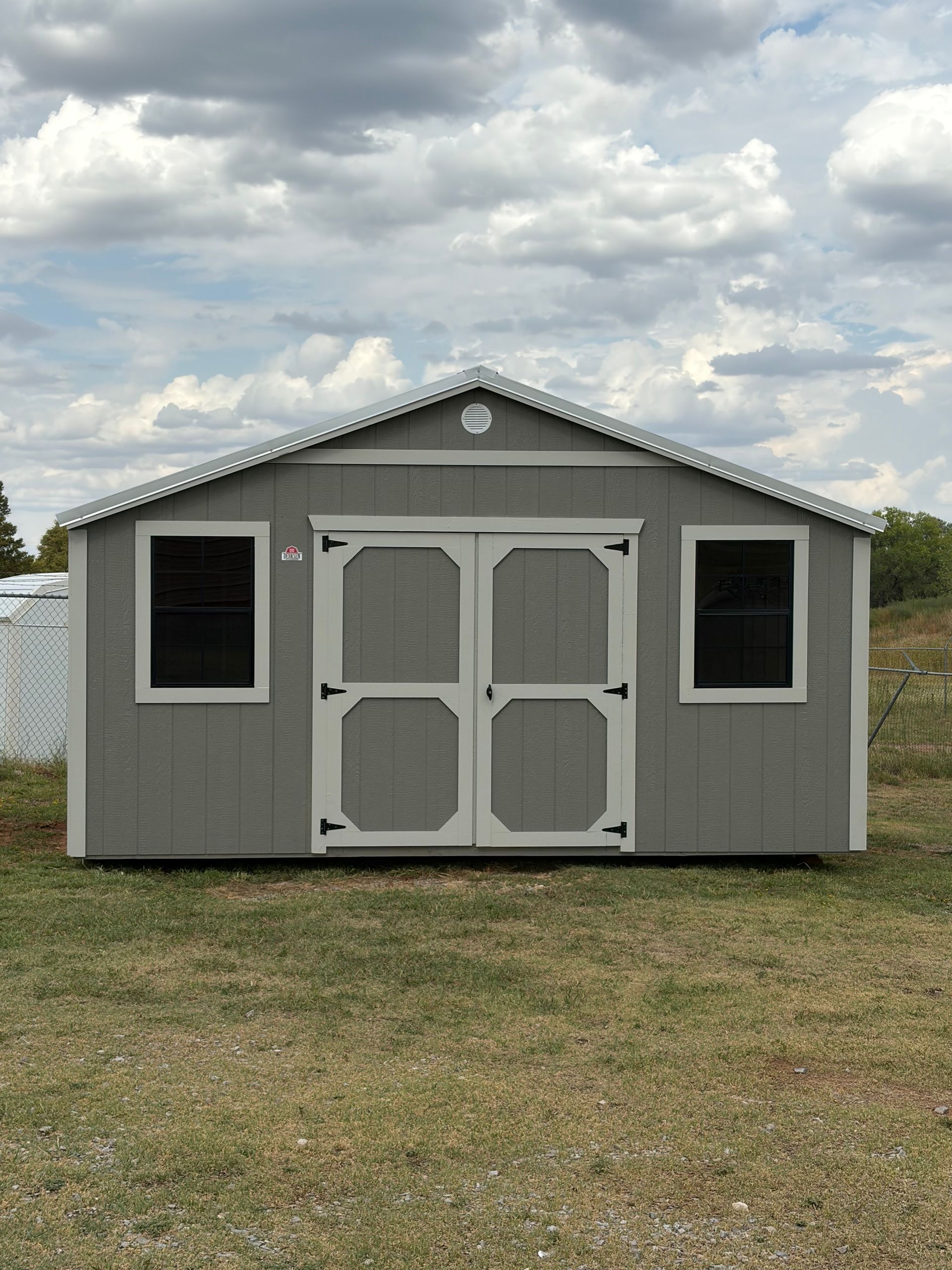 Explore the Derksen 10x16 Best Value Wood Side Utility with black windows, Smoke Paint siding, and a Galvalume Metal roof. Perfect for storage!