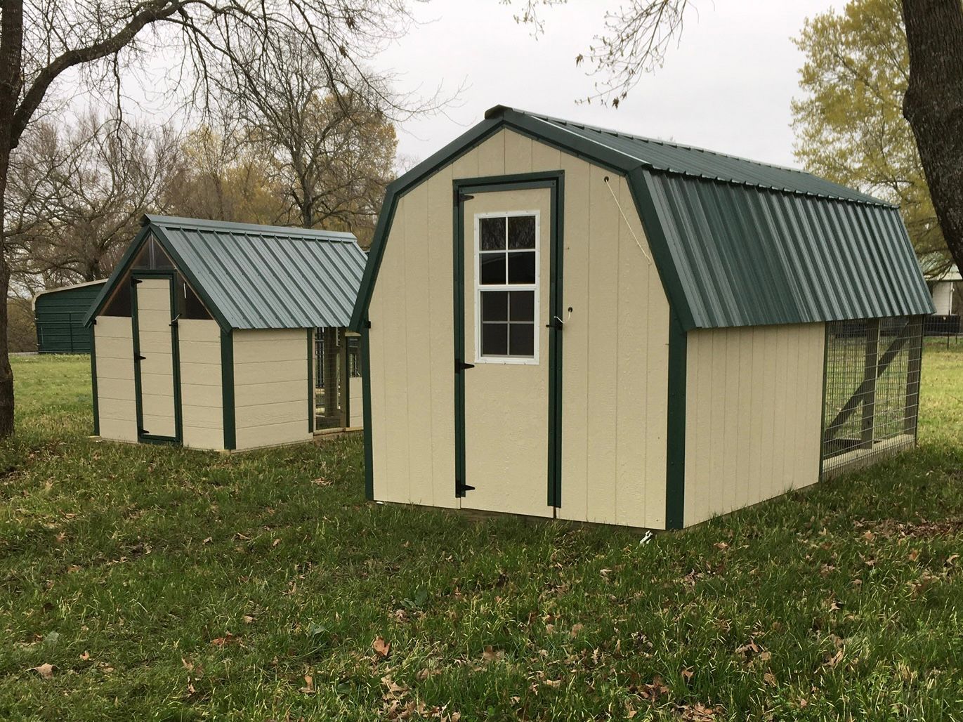 two chicken coops are sitting next to each other in a grassy field .