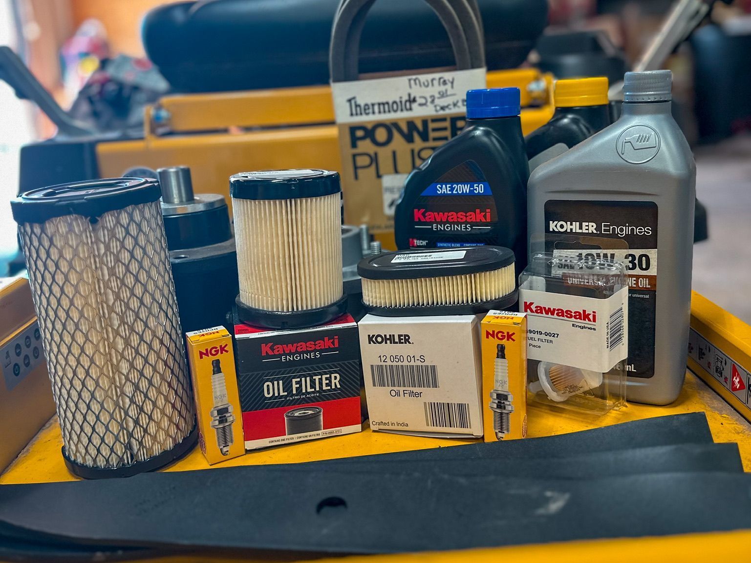 A yellow tray filled with lawn mower parts and oil.