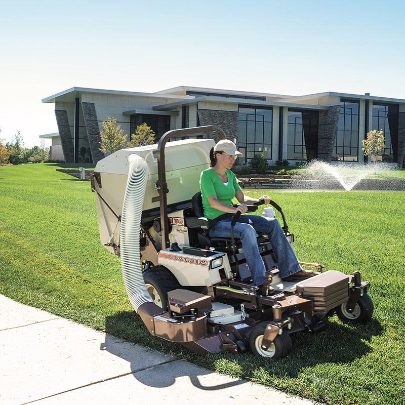 a woman is riding a lawn mower that says grasshopper on it