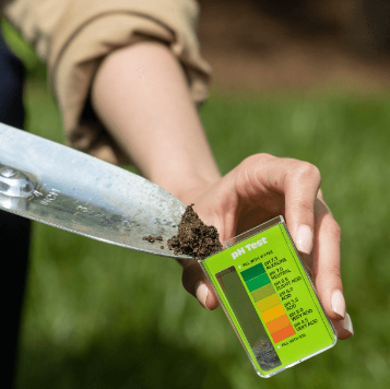 A person is holding a shovel and a card that says ph test