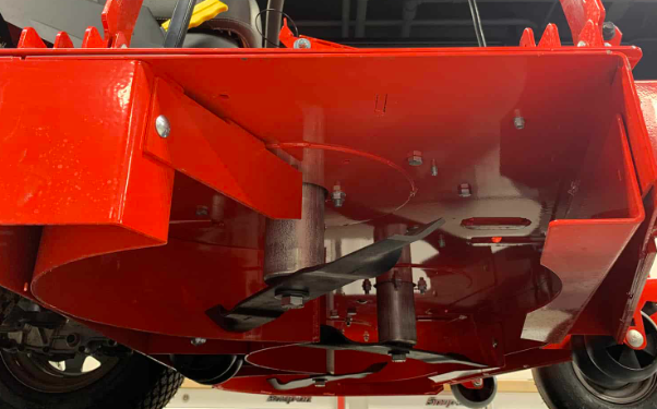 The underside of a red lawn mower is shown.
