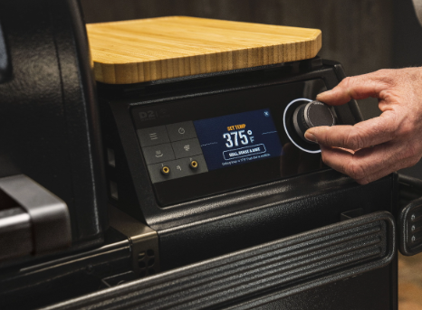 A person is adjusting the temperature on a grill.