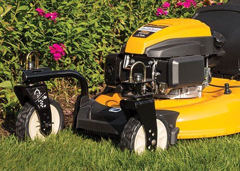 A yellow lawn mower is sitting on top of a lush green lawn.