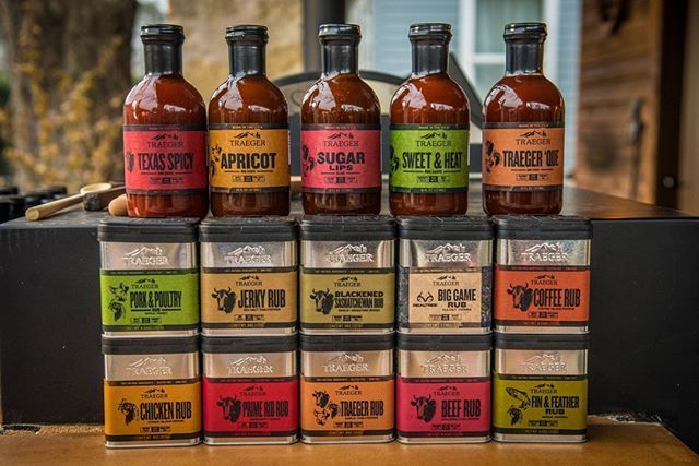 A row of bottles of barbecue sauce and spices on a table.