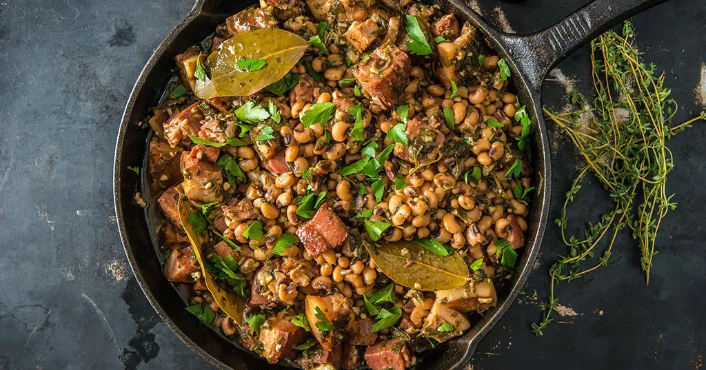 A skillet filled with beans and meat on a table.