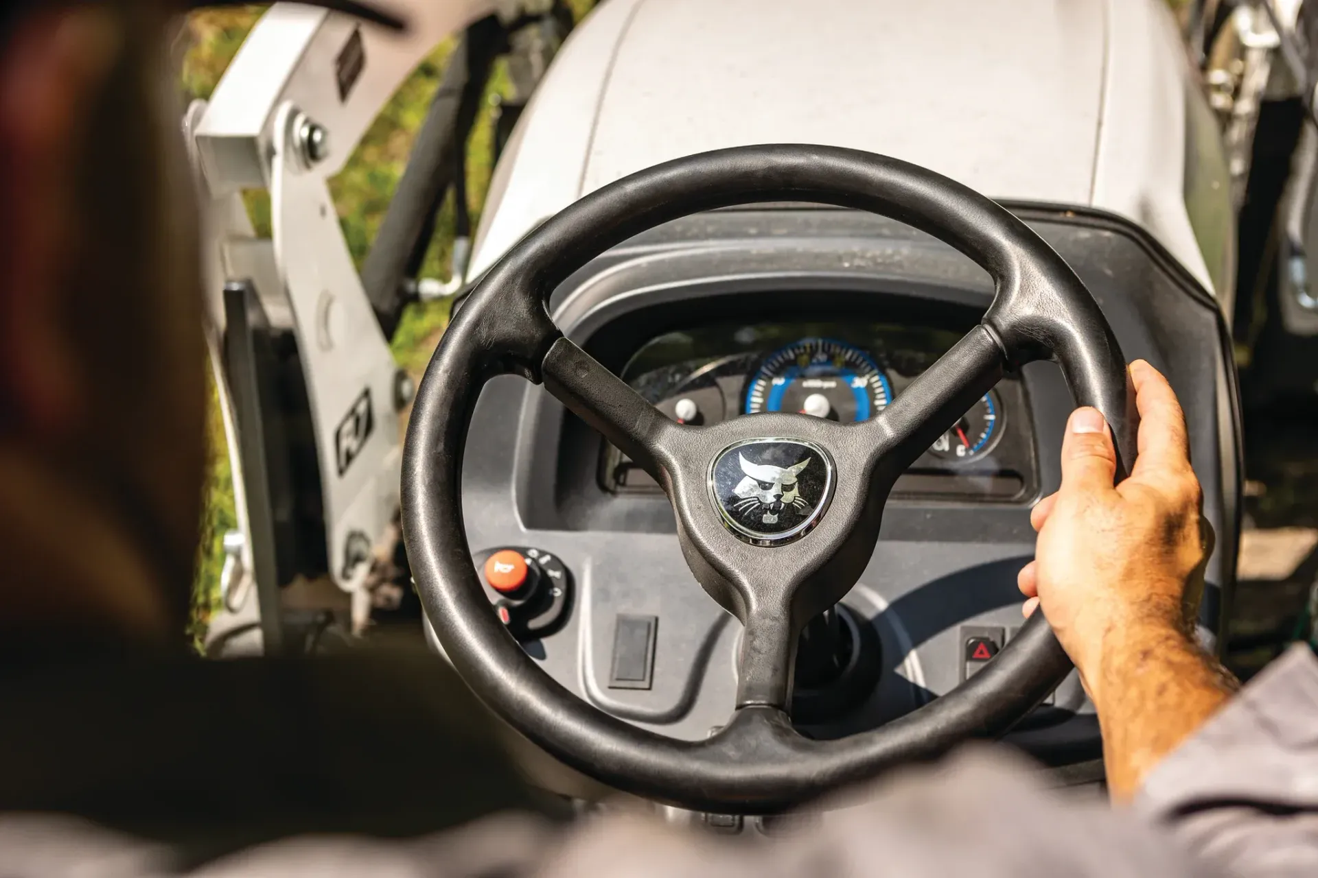a man is driving a tractor with a steering wheel .