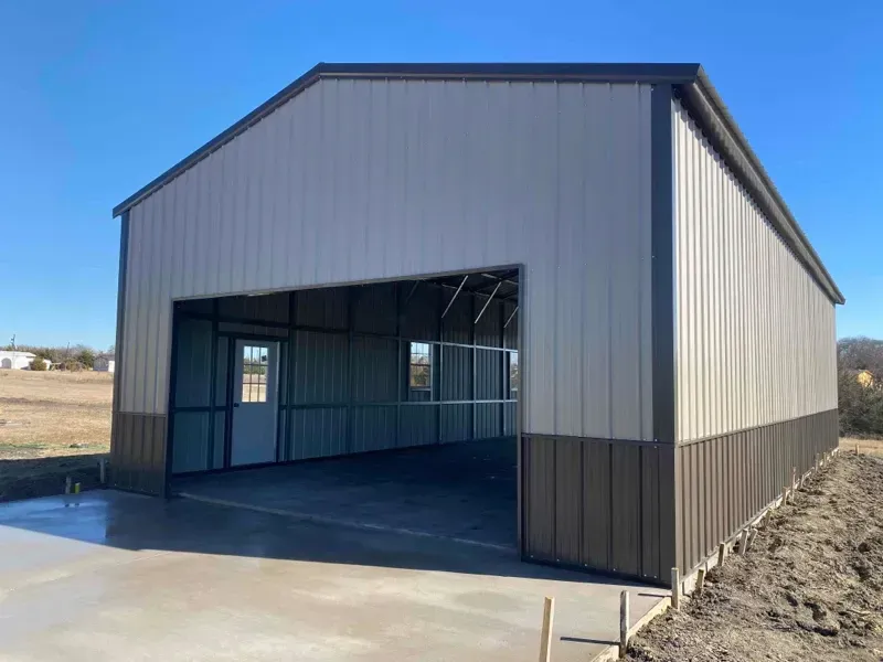 Gray metal garage with open front on a concrete pad under a clear blue sky