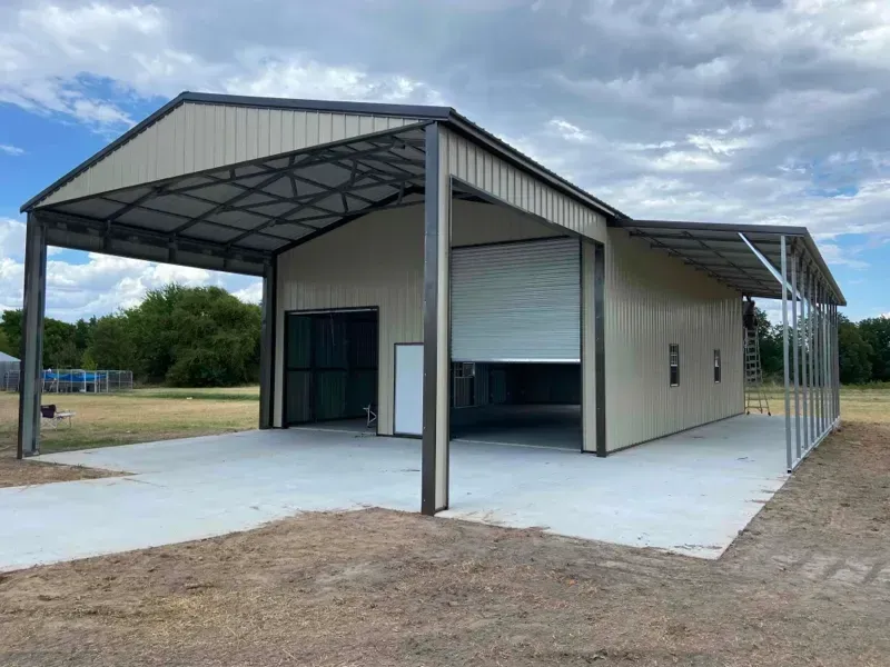 Open-sided metal building with a concrete slab and large front awning on a rural lot