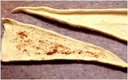 two pieces of dough with cinnamon on them are sitting on a table .