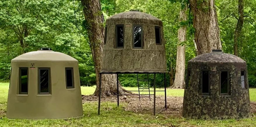 Three shelters are sitting on top of a lush green field.