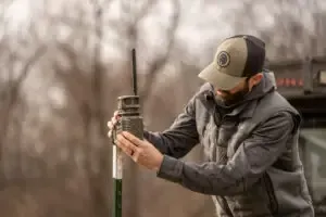 A man in a hat is holding a camera and looking at it.