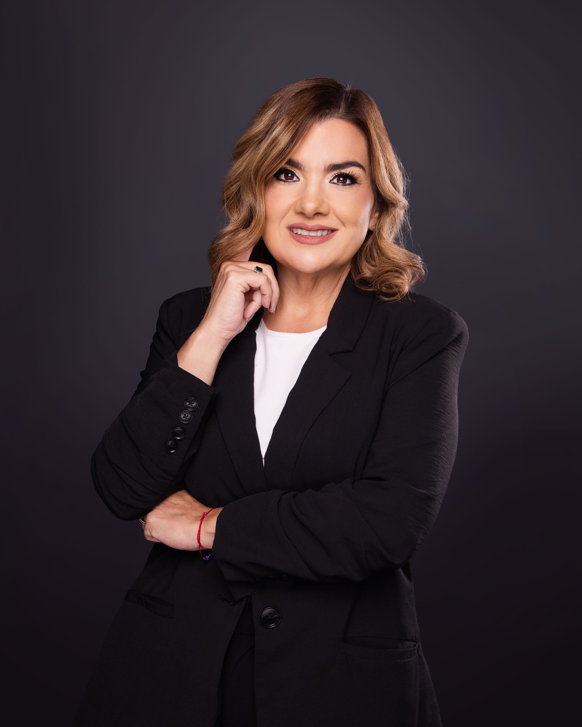 Portrait of a smiling professional in a black blazer against a dark background