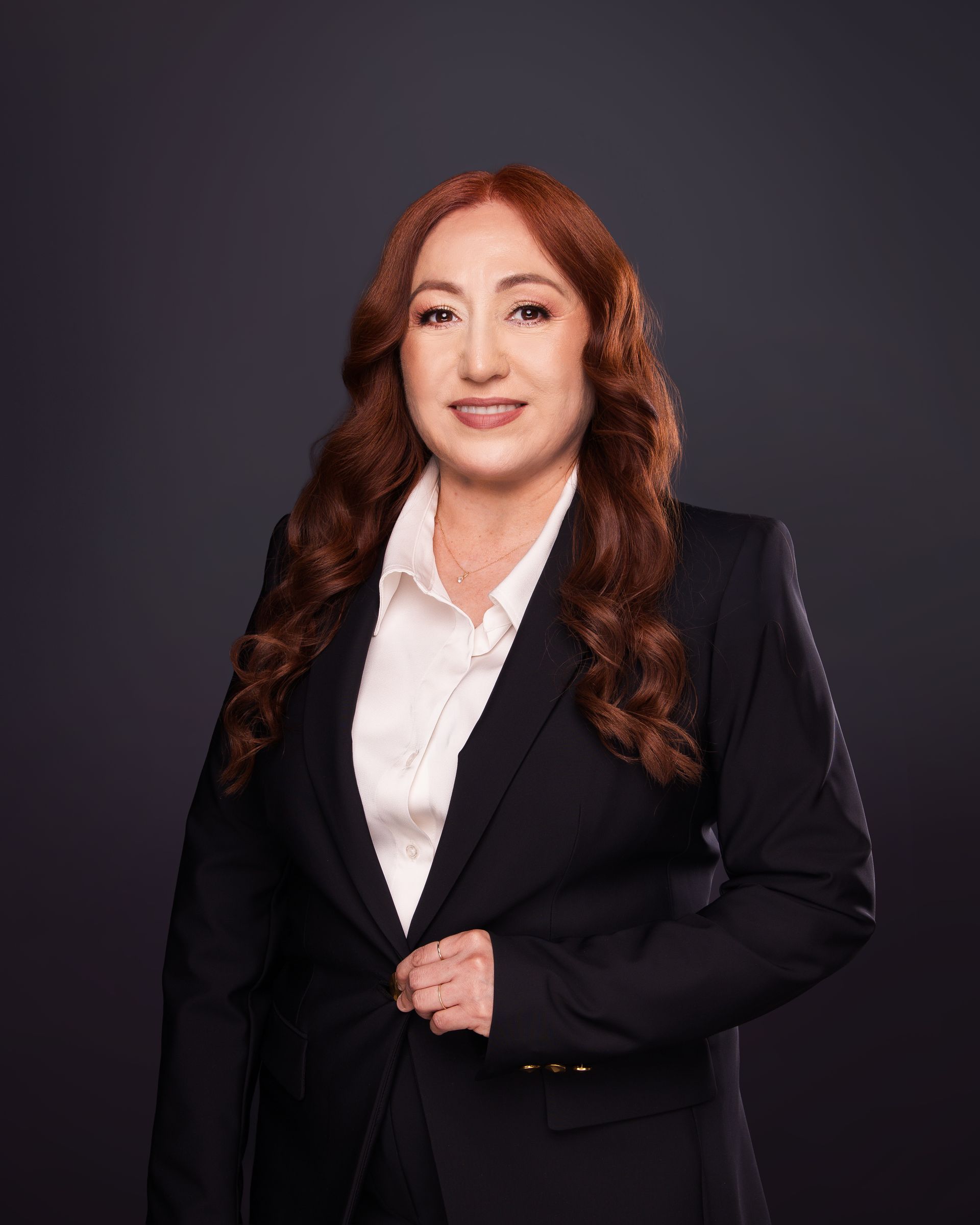 Studio portrait of a person in a black blazer and white shirt against a dark background