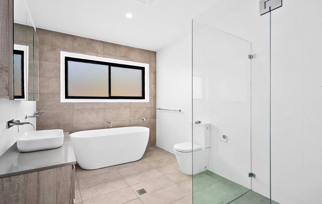 A House With Two Garage Doors and a Driveway Leading to It — LG Constructions in Thirroul, NSW