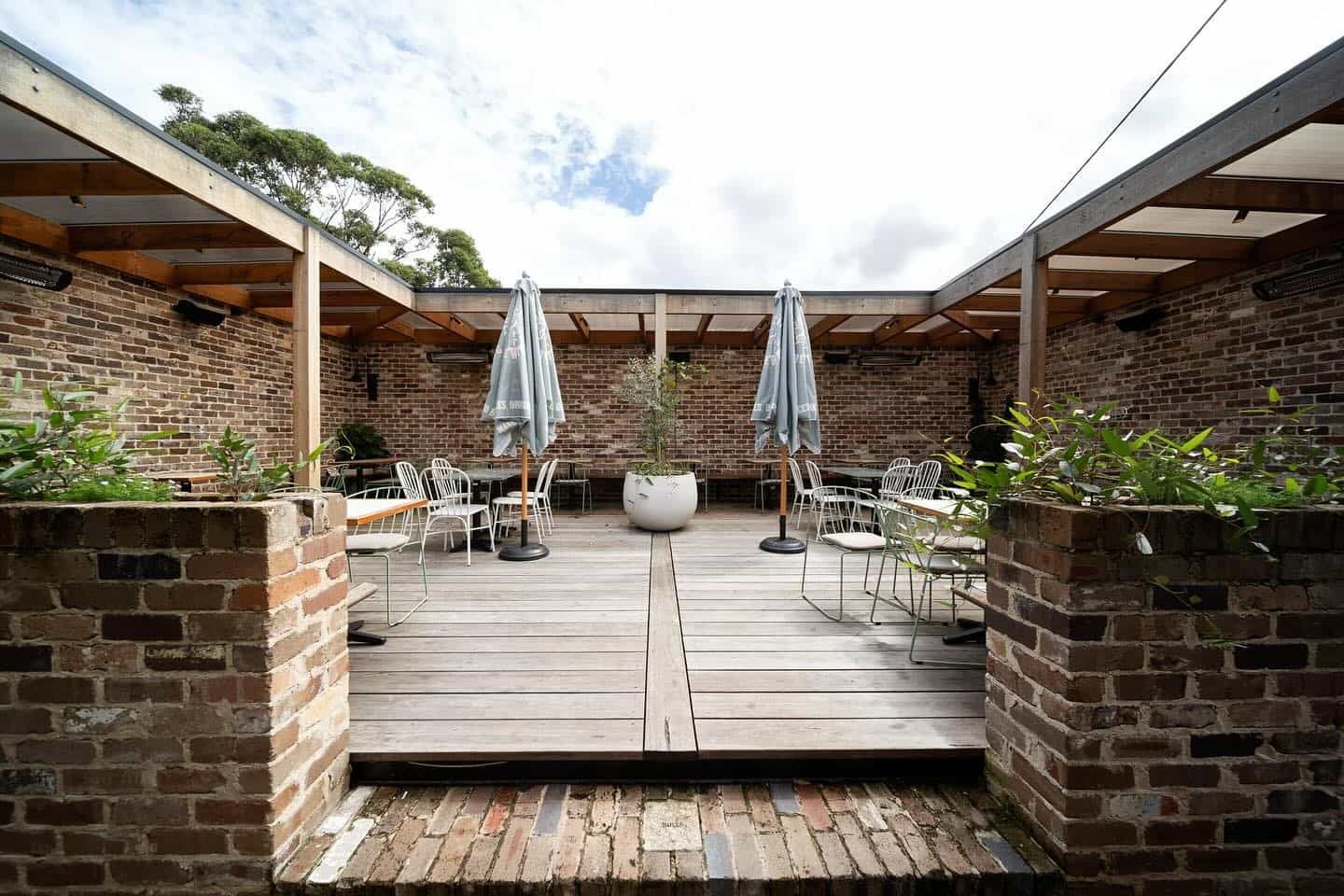 A Wooden Deck With Tables and Chairs Under a Pergola — LG Constructions in Thirroul, NSW