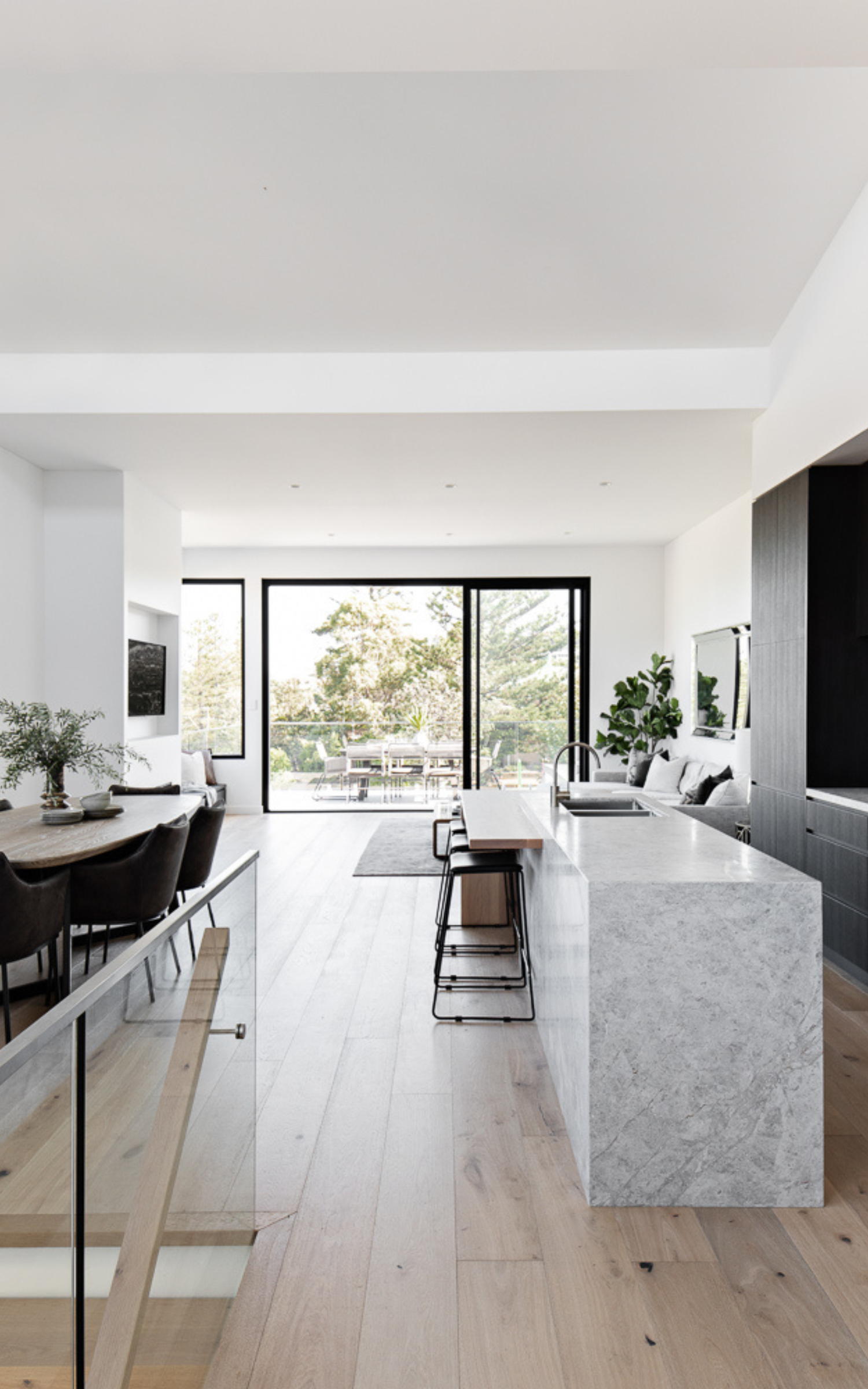 Bright modern kitchen with island, dining area, and large glass doors to a patio   — LG Constructions in Thirroul, NSW