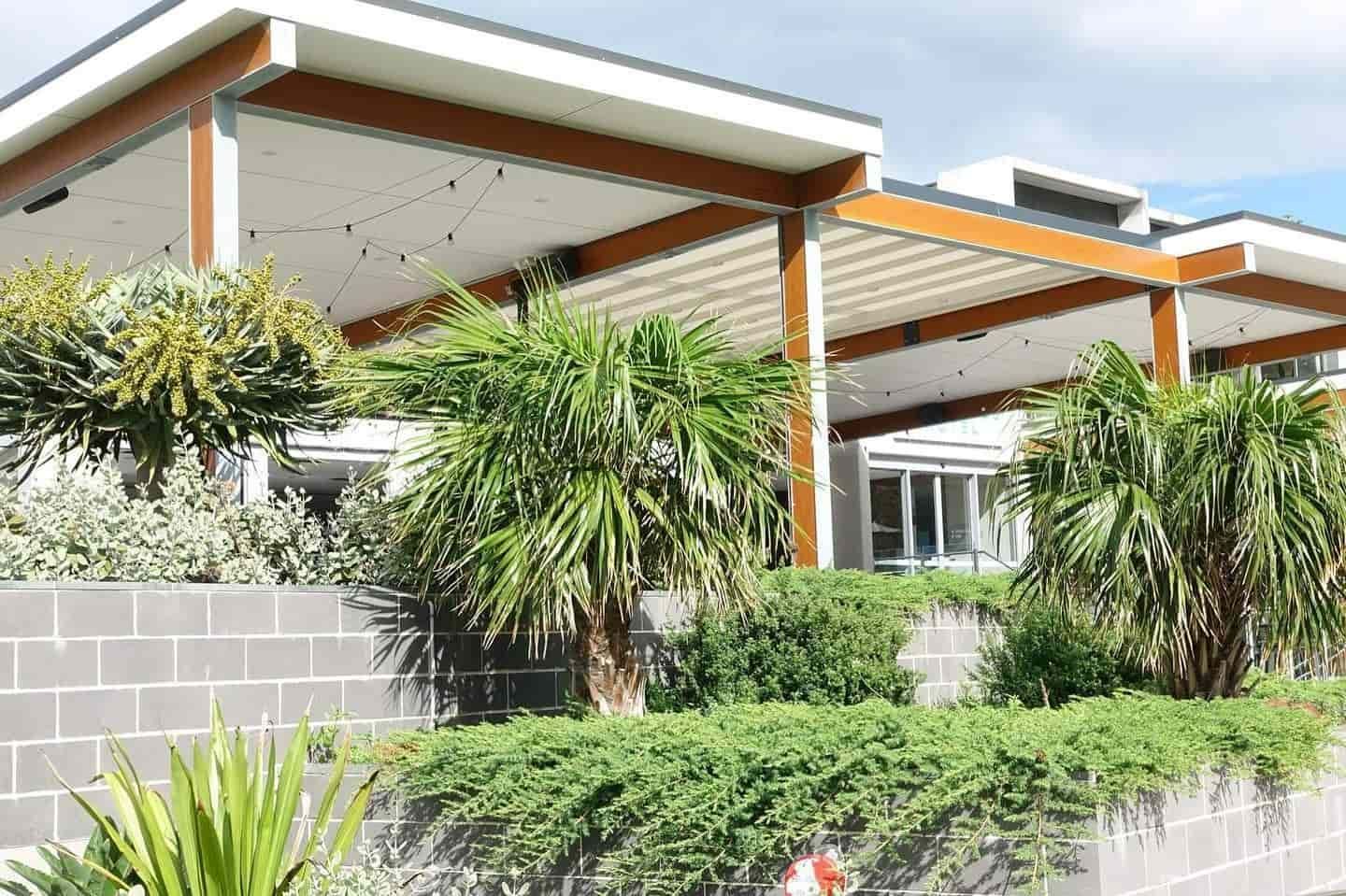 A House With a Pergola and Palm Trees in Front of It — LG Constructions in Thirroul, NSW