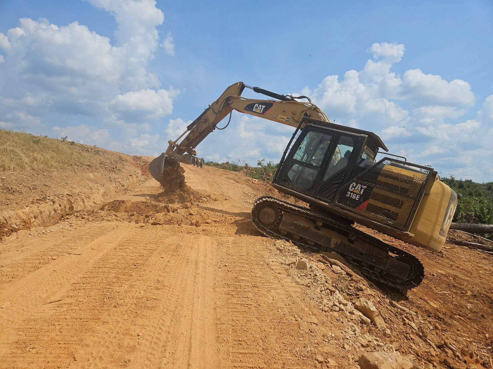 Yellow excavator digging into a dirt hillside on a sunny day.