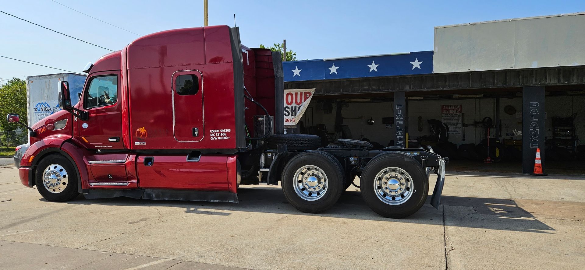 Red semi-truck parked in front of a building with blue and white stars.